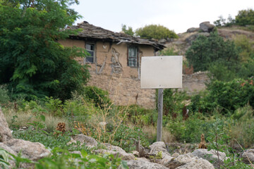 Old abandoned rural house in the Rhodope Mountains Bulgaria with an empty sign in front of it