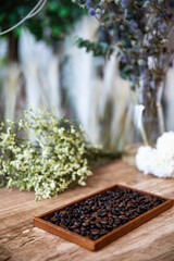 Roasted coffee beans in  behind beautiful flower background.