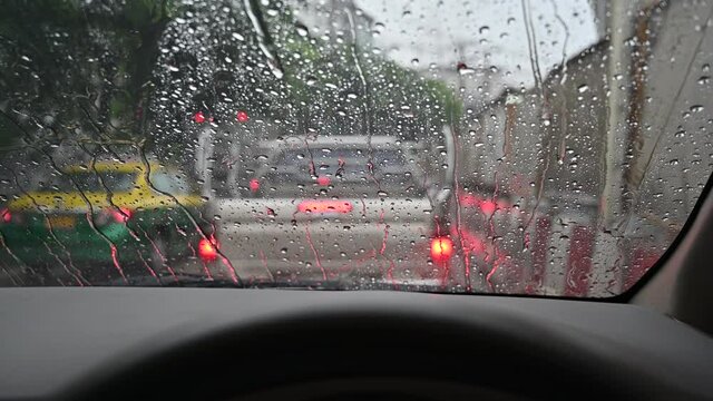 Raindrops run down on car windshield view. Traffic jam during the heavy rain storm.