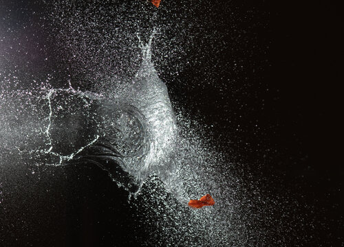 Splashes waterballoon bursting against black background and in a galaxy of water drops closeups
