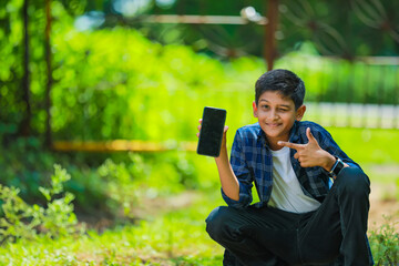 childhood, technology and people concept - indian cute school boy showing smartphone with blank screen