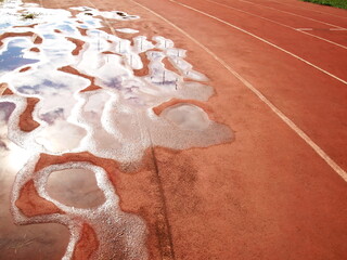Puddles on the running track. Rainwater trapped in a lot of puddles damages the surface of the...