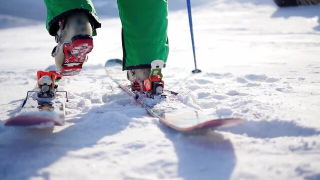 Skier attaches ski boots and skiing - back view