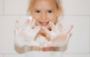 Smilling  little girl is washing hands.  Cute child showing soapy hands. Covid 19 - 382427200