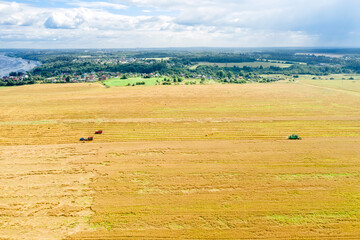 Obraz premium Top view of the field with harvesting equipment and the river leaving to the horizon