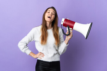 Young Ireland woman isolated on purple background holding a megaphone and smiling