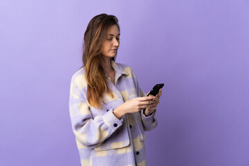 Young Ireland woman isolated on purple background sending a message or email with the mobile