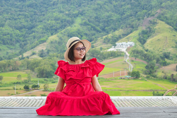 Fototapeta premium Woman in red dress sitting on wood terrace