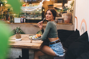 Pretty young woman enjoying bruschetta with salmon while sitting in modern cafe