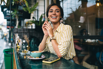Delighted female with toothy smile in cafe