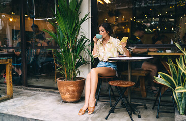 Woman drinking coffee and using smartphone