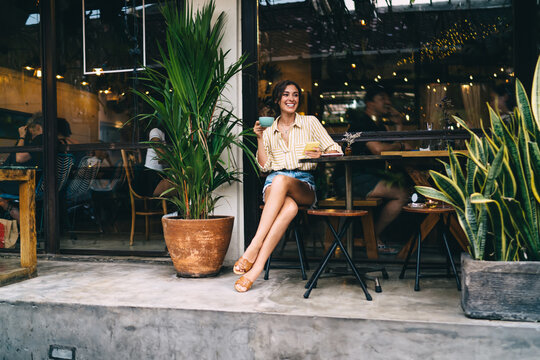 Positive woman with drink sitting at table