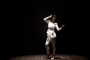 model in a white suit on stage in a beam of white light