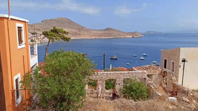 Rhodes, Greece: A blue van passing through narrow street of halki / chalki island located on a steep hill by aegean sea coast