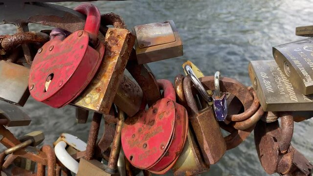 Close view of love padlocks on a bridge with nice depth of field, in the background a river. Handheld shot.