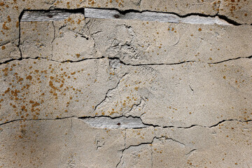 The old gray plastered wall of an industrial building with cracks and yellow biocorrosion. Grunge, retro. Texture. Space for text.