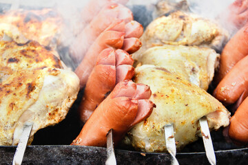Sausages are fried on the grill. Grilled meat. Chicken wings. Smoke