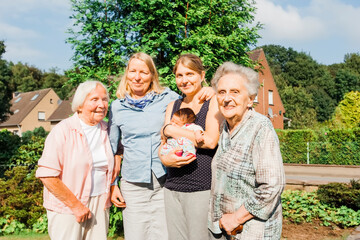 Women of happy multi-generational family with newborn girl outdoors