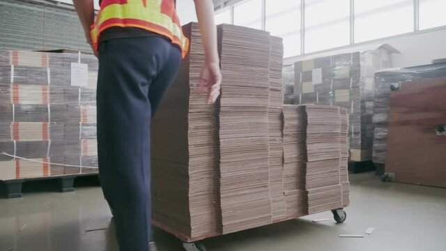 Asian woman factory worker doing arrangement cardboard paper to be stack for preparation process in warehouse room. Asia female wearing face mask while working in factory. New normal wear of people.