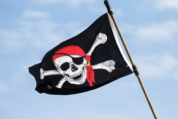 A skull and cross bones pirate flag is flying from a tall ship moored at St Augustine harbor,...