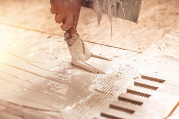 Worker or carpenter lay parquet flooring applied adhesive for parquet. Floor construction,...