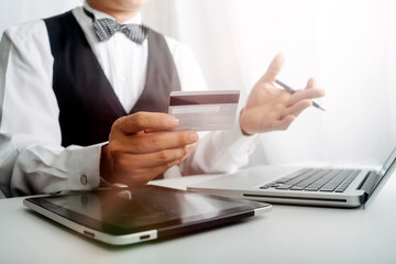 Business people use tablets and hold credit cards as an online shopping concept With a calculator and a book placed on the table