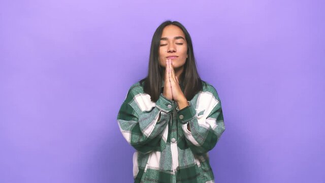 Young mixed race indian woman holding hands in pray near mouth, feels confident