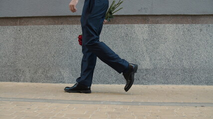 Businessman going on date outdoor. Man carrying flowers at stree