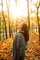 Portrait of young woman posing in nature at autumn park. Stylish woman relaxes and has a rest in the autumn forest. 