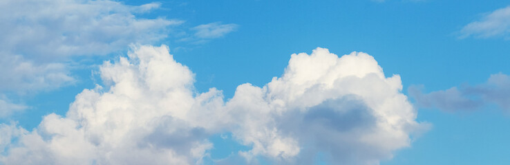 White curly clouds on a blue sky in sunny weather, panorama