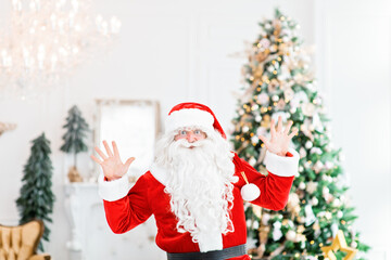 Happy Santa Claus indoors near christmas tree carrying no gifts to children