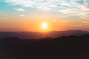 Sunset between mountains with clouds and colorful sky