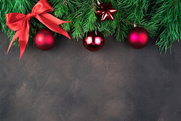 Red balloons and a bow on green pine branches on a brown concrete background. Holiday background top view. The concept of the new year 2021 and Christmas.