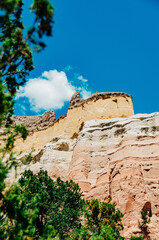 Colorful cliff walls in the high desert of New Mexico with a blue sky and green trees - 382445012