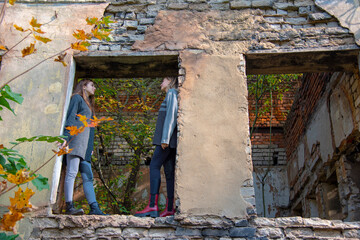 Two teenage girls stand in the window opening of an old abandoned dilapidated building on a Sunny...