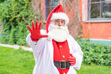 Fototapeta na wymiar Santa claus in a protective suit shows a stop gesture with his palm. Stop the spread of the coronavirus