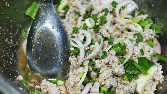 Cooking mixing Thai food Spicy Minced Pork Salad in bowl at kitchen , traditional Thai style local food