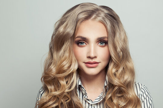 Perfect young woman with long curly blonde hairdo on white