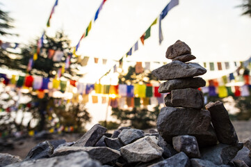 'Selective focus' Close-up view of some rocks naturally balanced on top of one another and some blurred prayer flags in the background. Dharamsala, India.