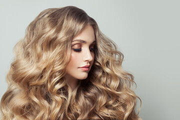 Portrait of nice woman with long healthy curly blonde hairstyle on white