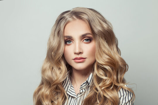 Healthy young woman model with long curly blonde hair on white