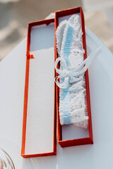 Sexy and rommantic brides soft blue white garter in the bright red gift box. Wedding day accessories.