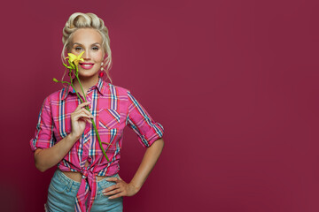 Pin-up woman with makeup and retro hairstyle holding flowers on pink banner background