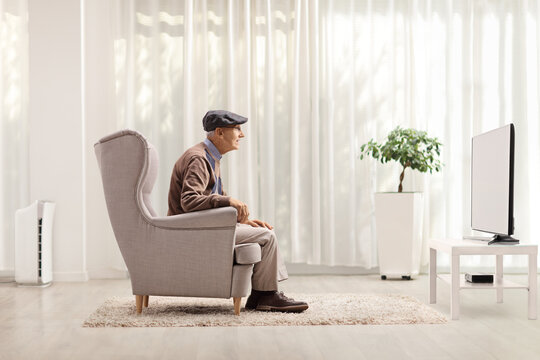 Elderly Man Sitting In An Armchair And Watching Tv
