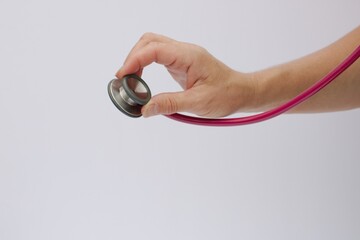 Forearm and hand viewed in image of Cacasian female nurse Positioned on Bell of Stethoscope reaching out toward Patient with white background