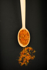 Top view of dry saffron in the wooden spoon on the dark background. Location vertical.