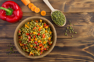 Top view of mung beans with vegetables in the bowl on  brown wooden the  background with copy space