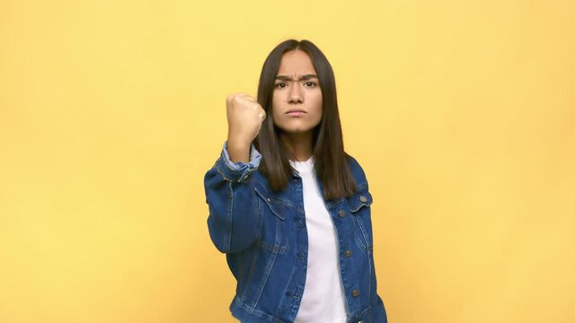 Young mixed race indian woman showing fist to camera, aggressive facial expression