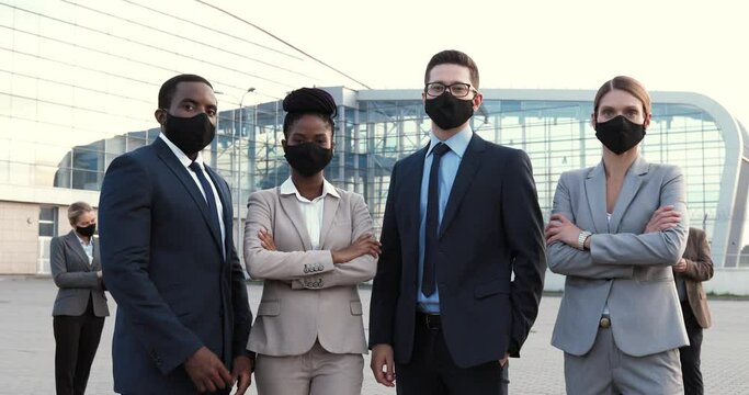 Portrait of mixed-races businessmen and businesswomen in masks and official style standing in urban city and looking at camera. Multi ethnic males and females business partners Men an women colleagues