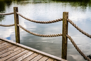 Naklejka premium wooden rope fence on the bridge over the pond